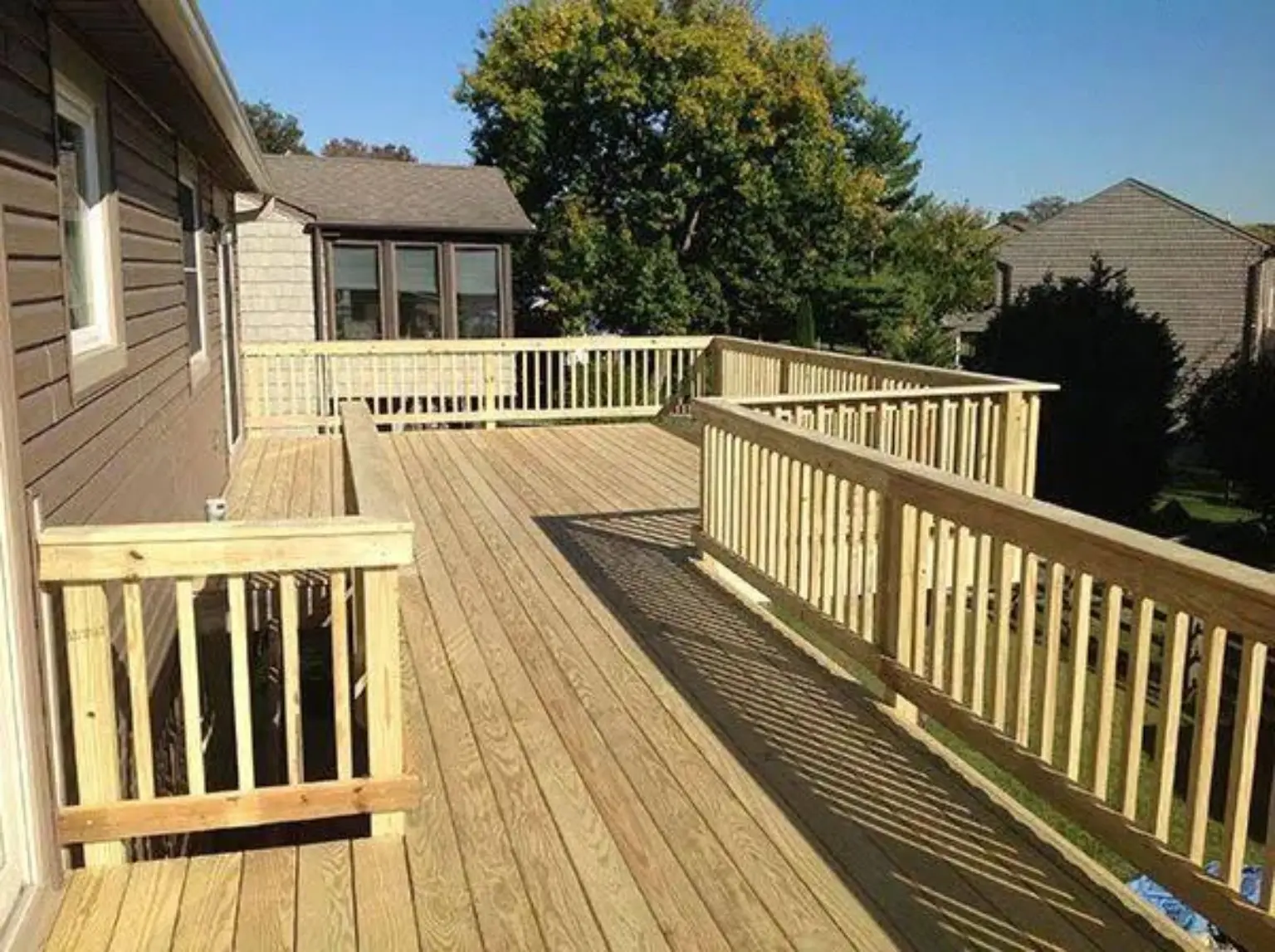 Large raised wood deck with railings wrapping around the platform