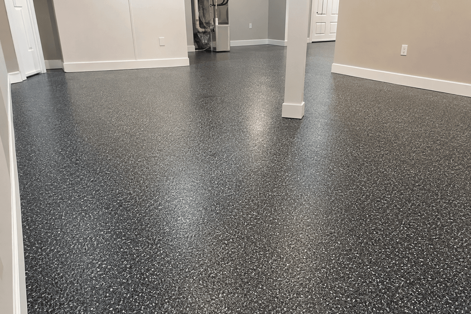Low-angle view across a dark flake epoxy basement floor