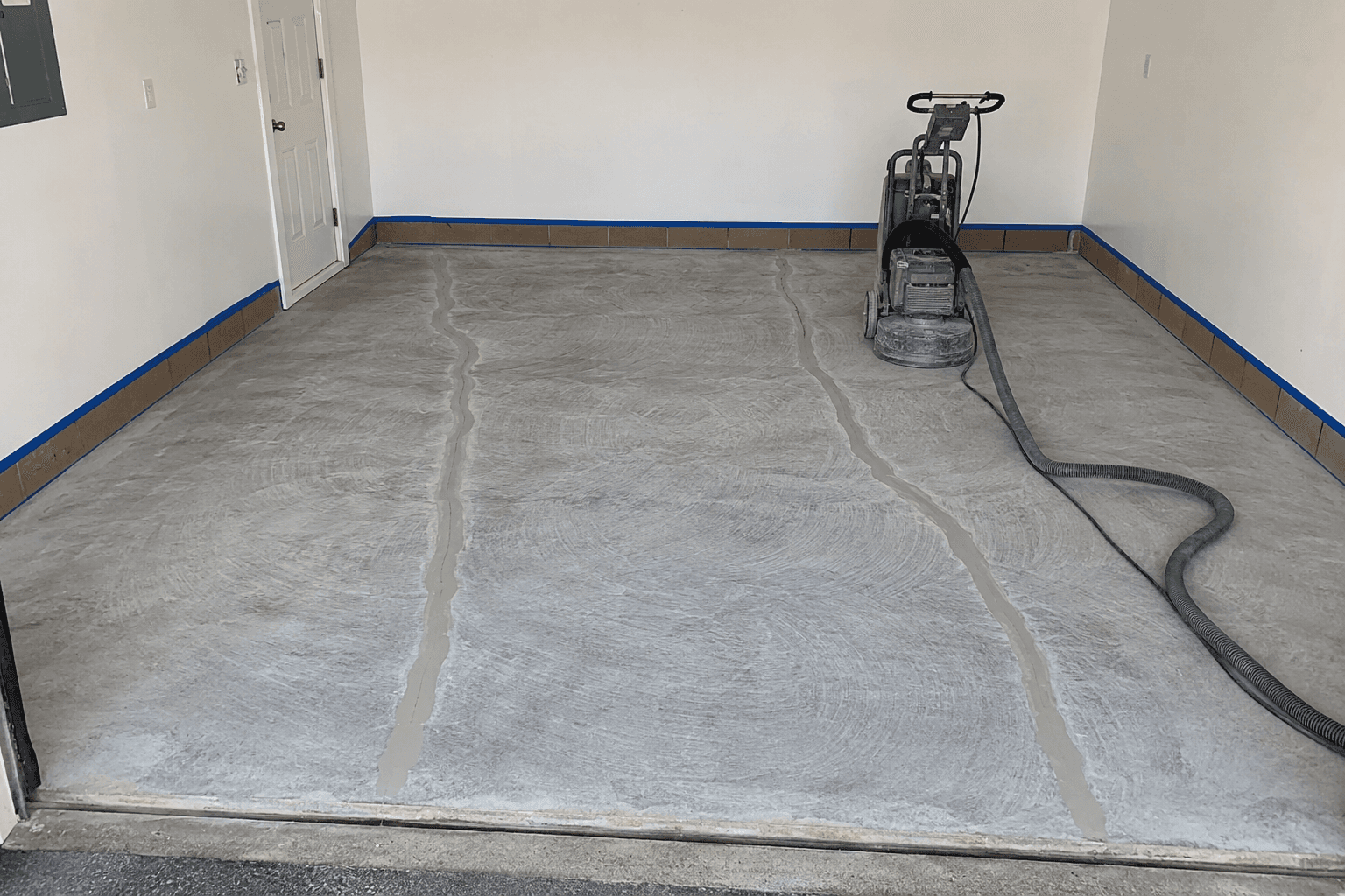Concrete garage floor prepared with repaired cracks and edge masking