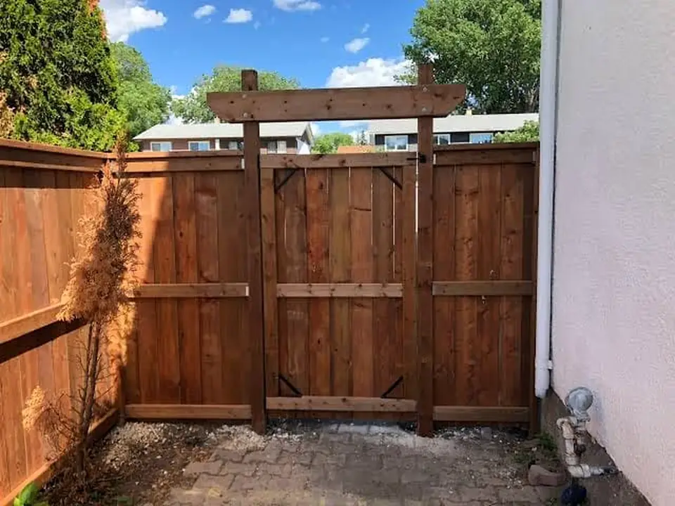 Wood gate and fence installation beside a home