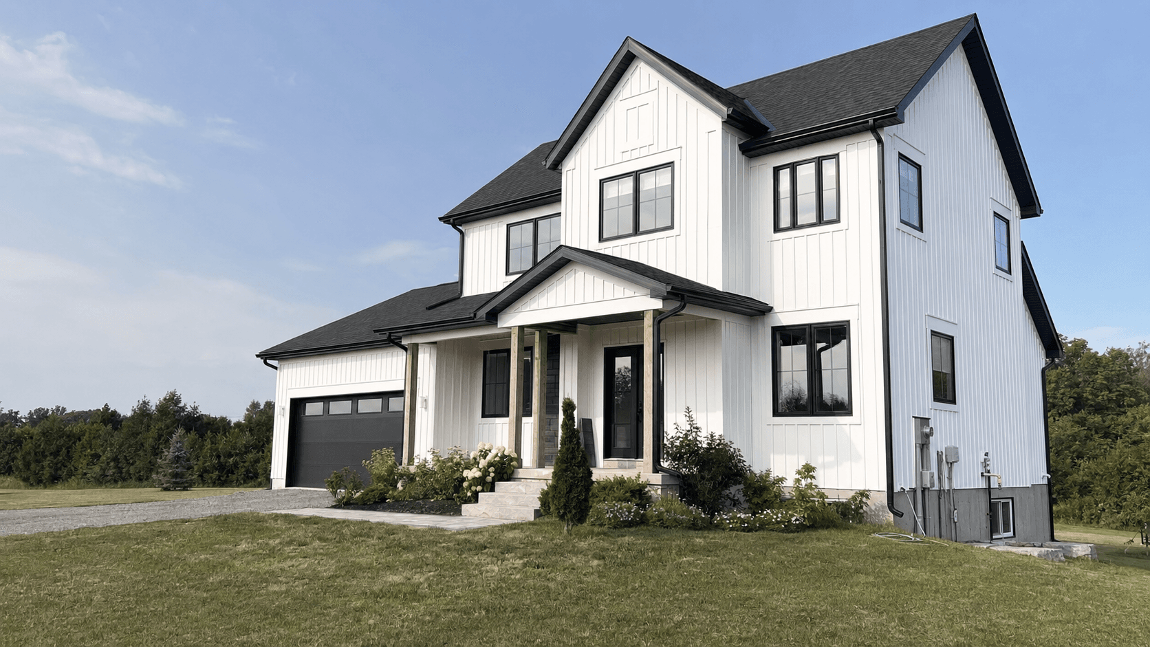 White two-storey home with black trim, a covered entry, and an attached garage
